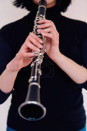 Foto de Una talentosa música morena exhibe su arte mientras sostiene con gracia y toca el clarinete sobre un fondo blanco prístino - Imagen libre de derechos