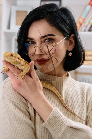 Photo for A young woman poses with her two pets, a bearded dragon and a stick insect, in this heartwarming photo. - Royalty Free Image