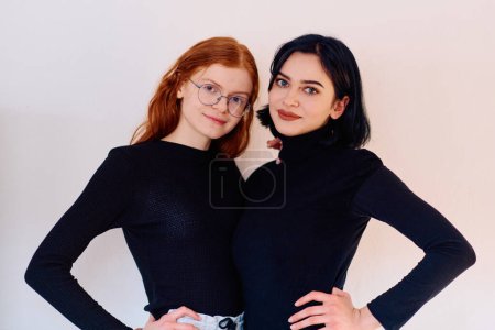Photo for Two sisters, one brunette and one redhead, share a tender embrace, epitomizing the enduring bond of sisterhood against a backdrop of pristine white. - Royalty Free Image