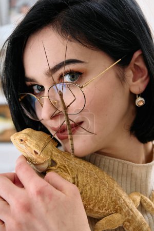 A young woman poses with her two pets, a bearded dragon and a stick insect, in this heartwarming photo.