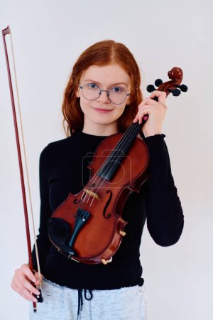 Une superbe musicienne rousse respire l'élégance en posant avec son violon, incarnant à la fois la grâce et les prouesses musicales.