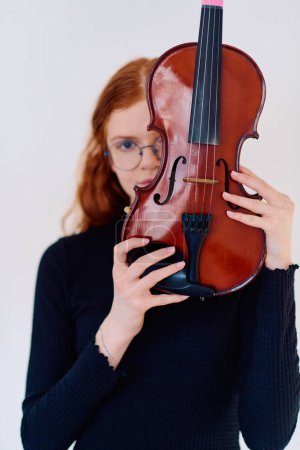 Téléchargez les photos : Une superbe musicienne rousse respire l'élégance en posant avec son violon, incarnant à la fois la grâce et les prouesses musicales. - en image libre de droit