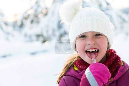 Foto de Linda niña mientras come carámbano en hermoso día de invierno. - Imagen libre de derechos