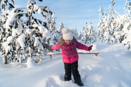 Begleiten Sie die bezaubernde Reise eines entzückenden Mädchens in ihrer gemütlichen Winterkleidung, während es fröhlich auf den sonnenverwöhnten Berghängen tobt und mit dem Schnee spielt..