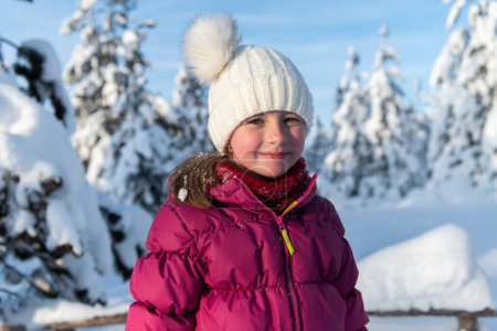 Téléchargez les photos : Une fille rayonnante sourit sur fond de montagnes enneigées, le soleil illuminant son expression joyeuse. - en image libre de droit