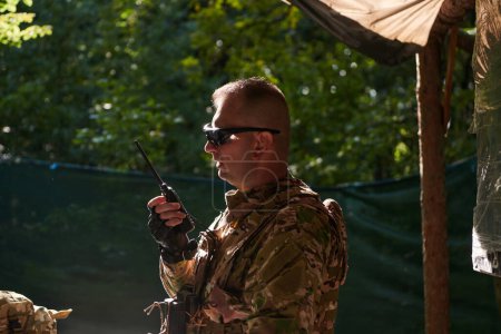 A military major employs a Motorola radio for seamless communication with his fellow soldiers during a tactical operation, showcasing professionalism and strategic coordination. 