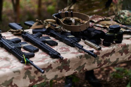Photo for An array of military weapons, including rifles and pistols, is meticulously arranged on a table in a military base, presenting a close-up view of the diverse firepower and armament meticulously - Royalty Free Image