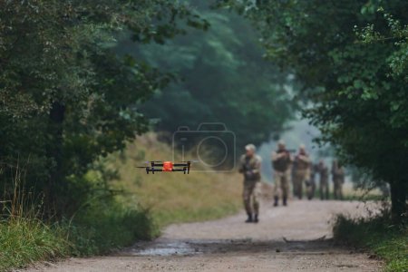 Foto de Unidad militar de élite desfilando y asegurando el bosque, utilizando drones para el escaneo y reconocimiento del terreno, mostrando sus habilidades avanzadas y entrenamiento especializado en operaciones de alto riesgo. - Imagen libre de derechos