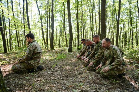 Foto de Un dedicado grupo de soldados se dedica a la oración islámica en medio de las difíciles y peligrosas condiciones de una operación militar en densas áreas boscosas. - Imagen libre de derechos