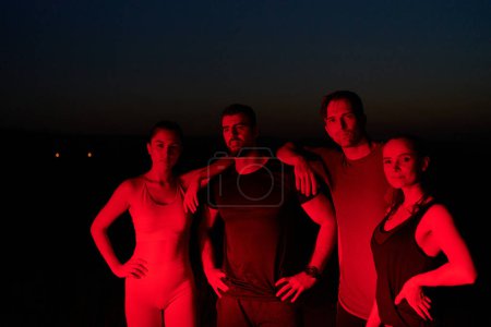 Photo for In the late-night hours, a diverse group of exhausted athletes find solace under a red glow, reflecting on their day-long marathon journey and celebrating camaraderie amidst fatigue. - Royalty Free Image