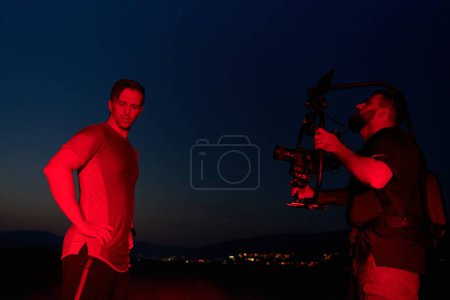 A skilled videographer captures the intensity of athletes running, illuminated by vibrant red lights, encapsulating the energy and determination of their nighttime training session.