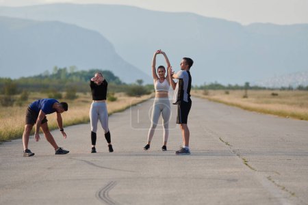 Photo for A determined group of athletes engage in a collective stretching session before their run, fostering teamwork and preparation in pursuit of their fitness goals. - Royalty Free Image