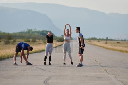 Photo for A determined group of athletes engage in a collective stretching session before their run, fostering teamwork and preparation in pursuit of their fitness goals. - Royalty Free Image