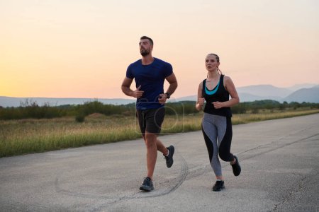 Una pareja vibrante corre al aire libre, encarnando la esencia del atletismo y el romance, sus pasos confiados que reflejan un compromiso compartido con la aptitud y la preparación para la futura maratón