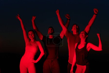 Photo for In the late hours of the night, a jubilant group of friends celebrates with cheers and embraces, reveling in the shared success of completing a long marathon. - Royalty Free Image