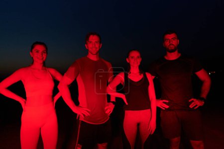Téléchargez les photos : Dans les heures tardives de la nuit, un groupe diversifié d'athlètes épuisés trouvent réconfort sous une lueur rouge, réfléchissant à leur journée de marathon et célébrant la camaraderie dans la fatigue. - en image libre de droit