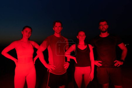 Téléchargez les photos : Dans les heures tardives de la nuit, un groupe diversifié d'athlètes épuisés trouvent réconfort sous une lueur rouge, réfléchissant à leur journée de marathon et célébrant la camaraderie dans la fatigue. - en image libre de droit