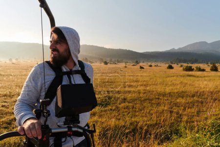Téléchargez les photos : Au petit matin brumeux, un vidéaste préparé se tient prêt à capturer la beauté sereine de la prairie dans des séquences cinématographiques - en image libre de droit