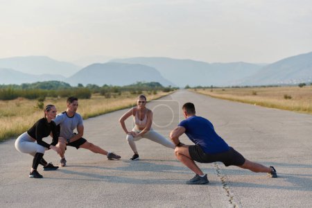 A determined group of athletes engage in a collective stretching session before their run, fostering teamwork and preparation in pursuit of their fitness goals.