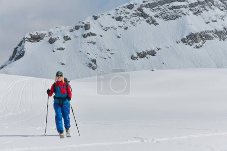 Téléchargez les photos : Un skieur déterminé escalade un sommet enneigé dans les Alpes, transportant des équipements d'arrière-pays pour une descente épique - en image libre de droit