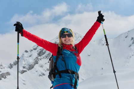 Téléchargez les photos : Une skieuse professionnelle se réjouit après avoir gravi avec succès les sommets enneigés des Alpes. - en image libre de droit