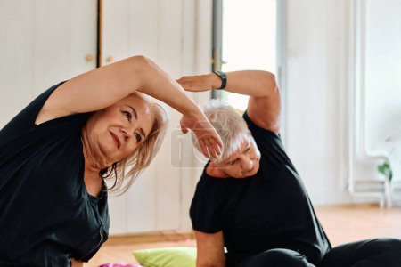 Téléchargez les photos : Un groupe de femmes âgées se livrent à divers exercices de yoga, y compris le cou, le dos et les jambes, sous la direction d'un entraîneur dans un espace ensoleillé, favorisant le bien-être et l'harmonie. - en image libre de droit