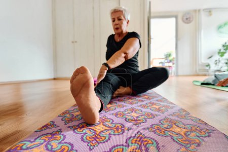 Photo for An elderly woman gracefully engages in various yoga poses, stretching her limbs and finding serenity in a modern sunlit space under the guidance of a trained instructor, embodying the essence of - Royalty Free Image