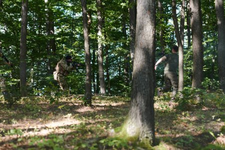 Foto de Un soldado de élite, camuflado y navegando sigilosamente a través de peligrosos terrenos boscosos, ejecuta una misión encubierta en una zona forestal aislada. - Imagen libre de derechos