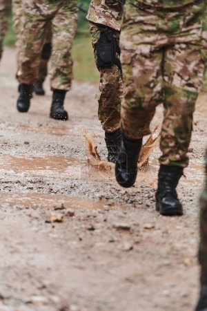 Téléchargez les photos : Photo rapprochée, les jambes résistantes des soldats d'élite, vêtus de bottes de camouflage, marchent délibérément le long d'un sentier forestier dangereux alors qu'ils entreprennent une mission militaire à enjeux élevés. - en image libre de droit