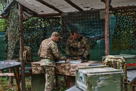 Une unité militaire hautement entraînée élabore des stratégies et organise une mission tactique tout en étudiant une carte militaire lors d'une séance d'information. 