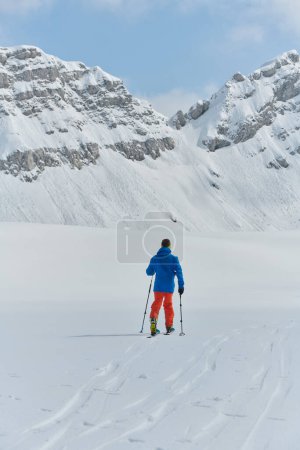 Foto de Un esquiador solitario se enfrenta a los elementos en una peligrosa subida a la cima de un pico alpino. - Imagen libre de derechos