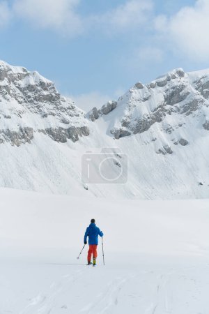 Foto de Un esquiador solitario se enfrenta a los elementos en una peligrosa subida a la cima de un pico alpino. - Imagen libre de derechos