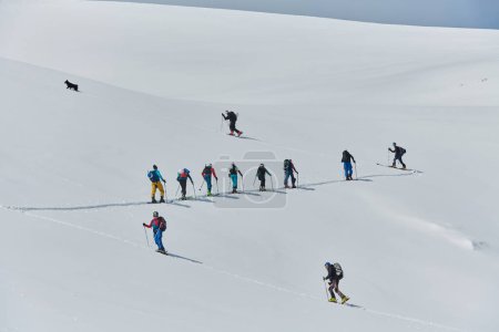 A group of professional ski mountaineers ascend a dangerous snowy peak using state-of-the-art equipment. 