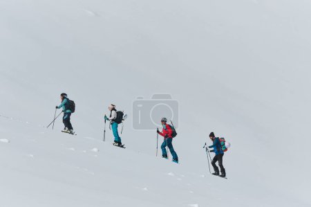 Eine Gruppe professioneller Skitourengeher besteigt mit modernster Ausrüstung einen gefährlichen schneebedeckten Gipfel. 