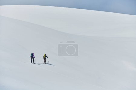 Téléchargez les photos : Dans une démonstration de travail d'équipe inébranlable et de détermination, deux skieurs professionnels gravissent les sommets enneigés des Alpes, unis dans leur quête du sommet. - en image libre de droit