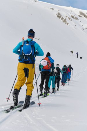 A group of professional ski mountaineers ascend a dangerous snowy peak using state-of-the-art equipment. 
