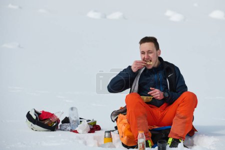 Foto de Un esquiador se detiene en una cresta cubierta de nieve para saborear un momento de paz y disfrutar del impresionante panorama alpino. - Imagen libre de derechos