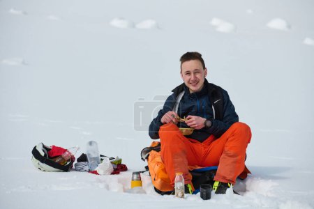 Téléchargez les photos : Un skieur s'arrête sur une crête enneigée pour savourer un moment de paix et admirer le panorama alpin à couper le souffle. - en image libre de droit