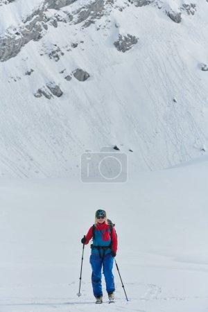 Téléchargez les photos : Un skieur déterminé escalade un sommet enneigé dans les Alpes, transportant des équipements d'arrière-pays pour une descente épique - en image libre de droit