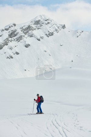 Photo for A female skier stands at the snowy summit of a mountain, equipped with professional gear and skis, poised for an exhilarating descent - Royalty Free Image