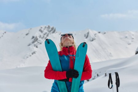 Téléchargez les photos : Une skieuse professionnelle se réjouit après avoir gravi avec succès les sommets enneigés des Alpes. - en image libre de droit