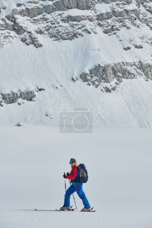 Foto de Una esquiadora se encuentra en la cima nevada de una montaña, equipada con equipo profesional y esquís, preparada para un emocionante descenso - Imagen libre de derechos