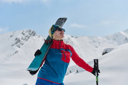 Eine professionelle Skifahrerin jubelt nach der erfolgreichen Besteigung der schneebedeckten Gipfel der Alpen.