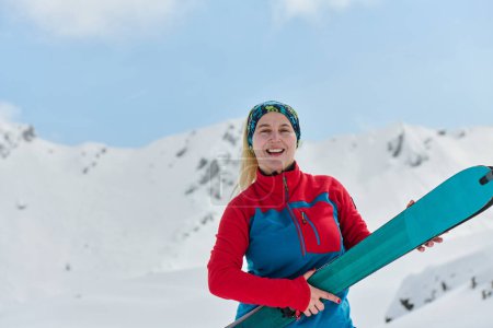 Foto de Una esquiadora triunfante viga con confianza sobre un pico nevado después de conquistar un desafiante ascenso. - Imagen libre de derechos