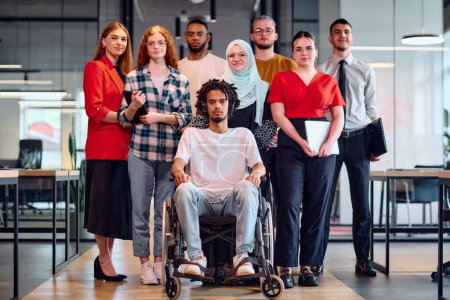 Photo for A diverse group of young business people walking a corridor in the glass-enclosed office of a modern startup, including a person in a wheelchair and a woman wearing a hijab. - Royalty Free Image