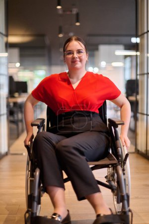 Eine moderne junge Geschäftsfrau im Rollstuhl ist von einem inklusiven Arbeitsbereich mit gläsernen Büros umgeben, der Entschlossenheit und Innovation in der Geschäftswelt verkörpert. 