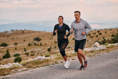 Una pareja vestida con ropa deportiva recorre un camino pintoresco durante un entrenamiento matutino, disfrutando del aire fresco y manteniendo un estilo de vida saludable..