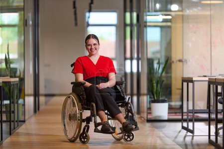 Eine moderne junge Geschäftsfrau im Rollstuhl ist von einem inklusiven Arbeitsbereich mit gläsernen Büros umgeben, der Entschlossenheit und Innovation in der Geschäftswelt verkörpert. 