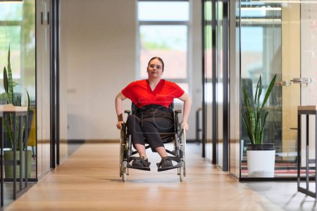 Una joven empresaria moderna en silla de ruedas está rodeada por un espacio de trabajo inclusivo con oficinas con paredes de cristal, que encarna la determinación y la innovación en el mundo empresarial. 