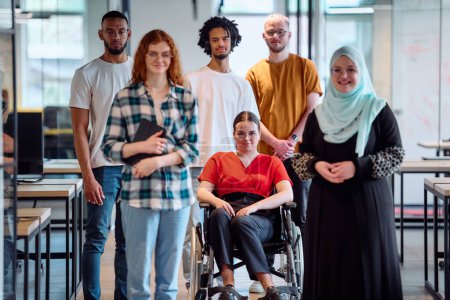 Eine bunte Gruppe junger Geschäftsleute spaziert durch einen Gang im verglasten Büro eines modernen Start-ups, darunter eine Person im Rollstuhl und eine Frau im Hidschab.